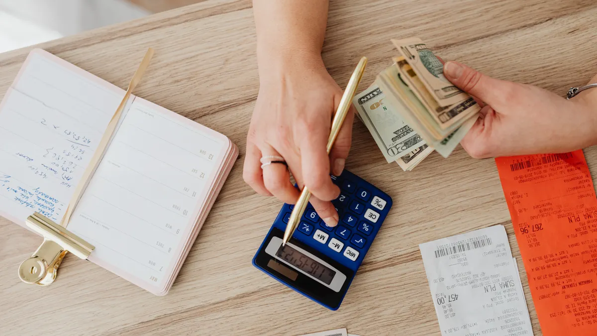 Cheap Family Cabins and Cottages Guide Hands counting cash with calculator, notebook, and receipts